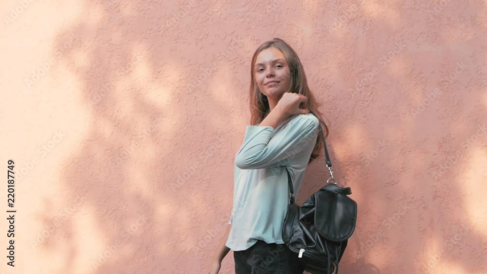 Adorable Brunette pretty Girl Posing and smiling on pink wall Background outdoors on sunny day