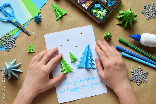 Making greeting card with origami 3D Xmas tree from paper. Merry Christmas and Happy New Year decoration. Children's DIY concept. Handmade crafts on holiday with your own hands.