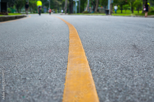 Close up of yellow line on the public park with people exercise and cycling for good health
