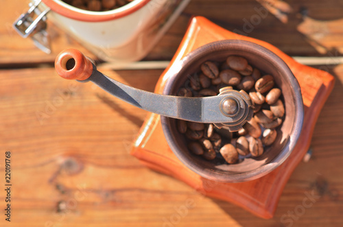 Manual coffee grinder with coffee beans on a wooden background