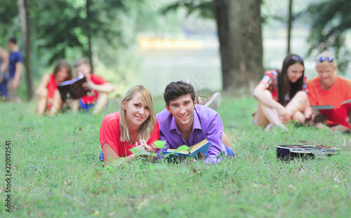 several pairs of students with books lying on the grass in the Park © yurolaitsalbert