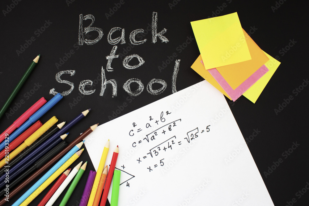 Back to school flat lay. Colour pencils, stickers and lesson notes on black background Back to school flat lay. Colour pencils, stickers and lesson notes on black background