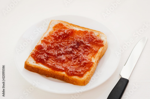 Toast with a crumpled apple jam on a plate on white table. Delicious sweet breakfast.