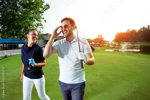 Portrait of smiling couple holding golf clubs while standing on field © zorandim75