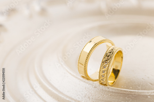 Two gold wedding rings on beige background