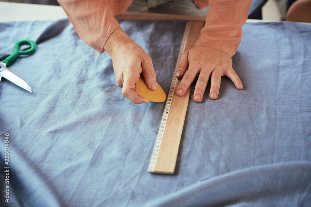 Hands of female tailor drawing garment details on fabric Hands of female tailor drawing garment details on fabric