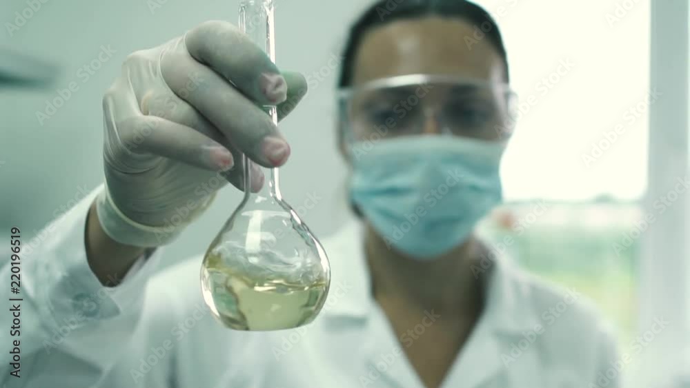 Girl lab assistant stirs the liquid in a flask Girl lab assistant stirs the liquid in a flask