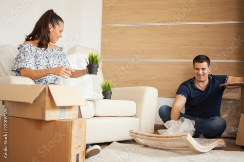 Young couple Moving in new home and unpacking carboard boxes.Almost done moving in. photo