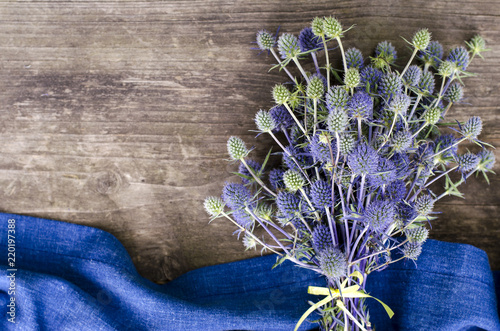 Field eryngium with blue textiles on a wooden table photo