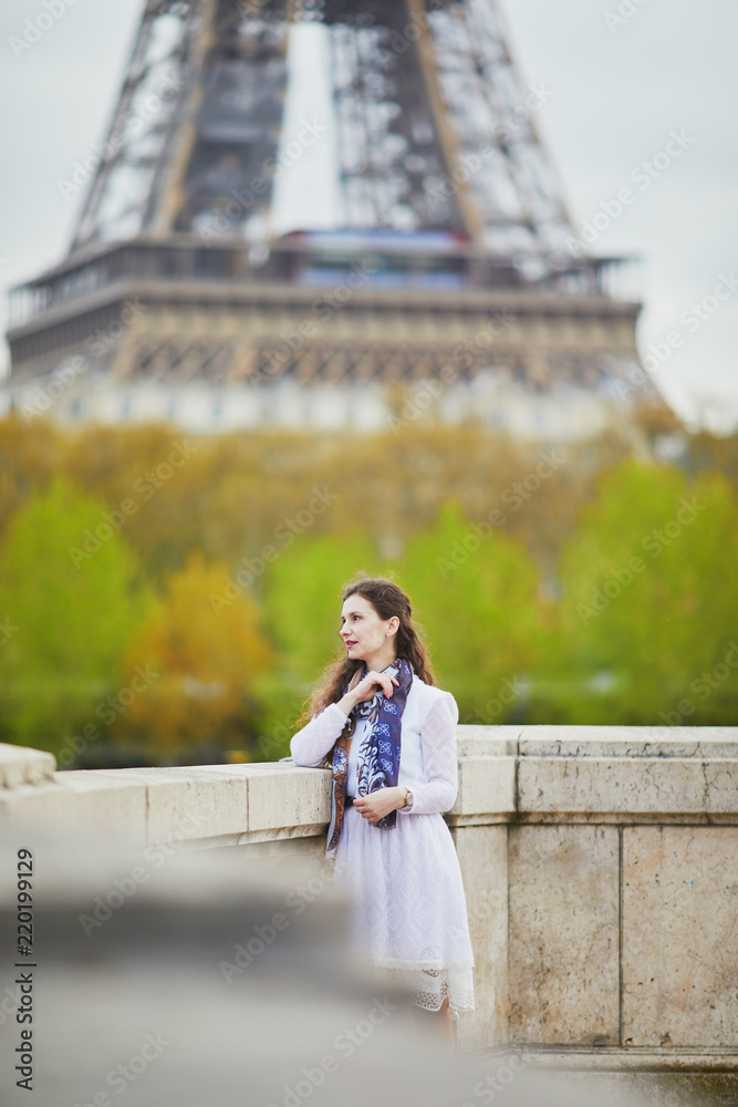 Woman in white dress near the Eiffel tower in Paris, France