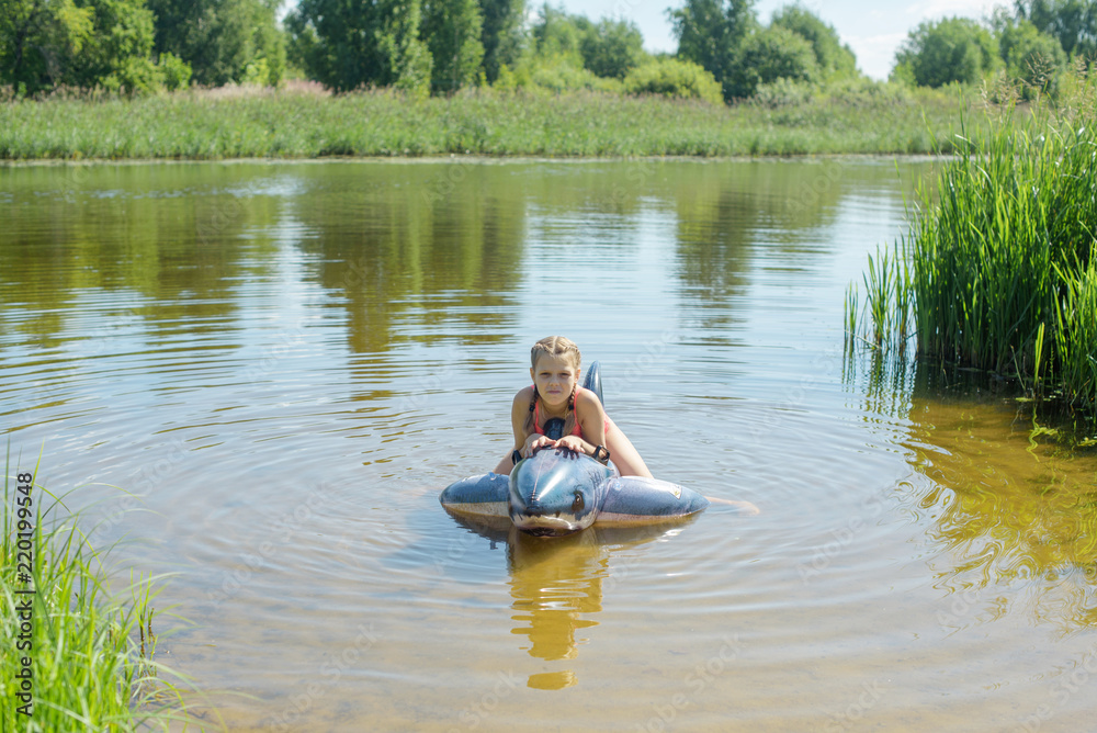girl swimming in the river on an inflatable shark girl swimming in the river on an inflatable shark