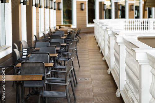 line of modern and comfortable tables and chairs in the restaurant balcony with classic white fence and big light windows