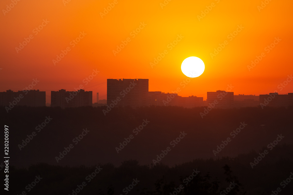 Fototapeta premium Dawn sun on the background of distant buildings