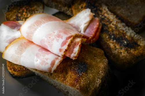 toasted bread toasts with a slice of bacon on a dark background