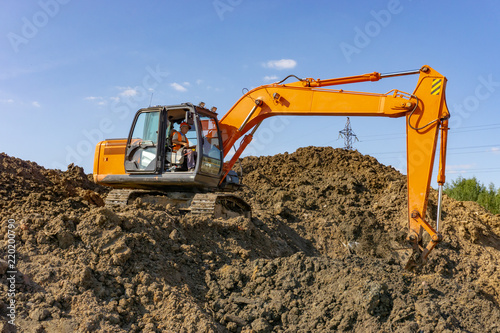 Orange excavator loads the land on a construction site..