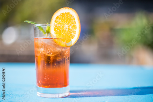 Glass of aperol spritz with mint and a orange slice on a sunny day.