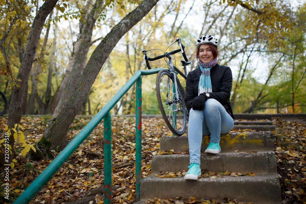 Photo of brunette sitting on stairs next to bicycle