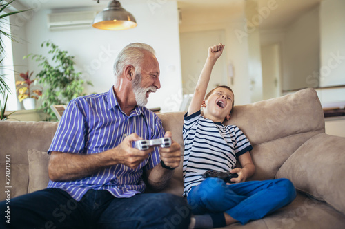 Grandfather and grandson are playing video games at home. photo