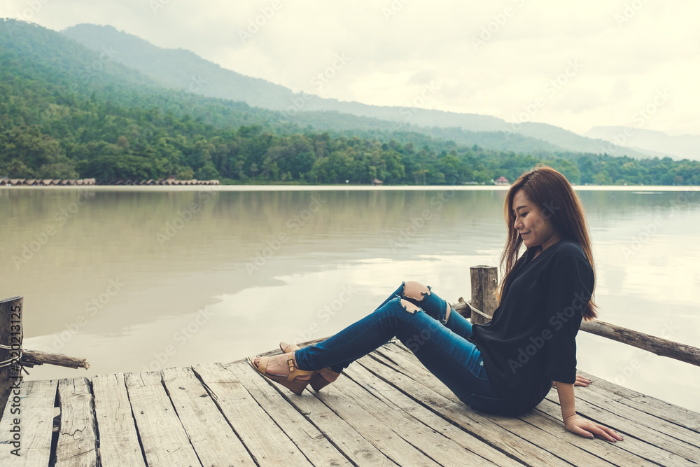 alone on an old wooden pier by the river with feeling happy , sky and mountain background