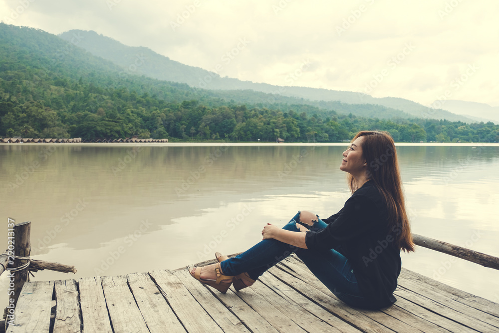 alone on an old wooden pier by the river with feeling happy , sky and mountain background alone on an old wooden pier by the river with feeling happy , sky and mountain background