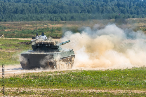 The military tank makes a shot at the enemy targets in the field.