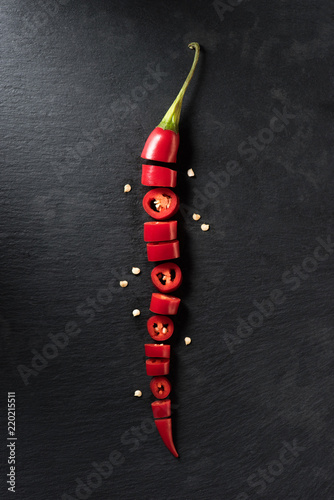 top view of cut red ripe chili pepper on black surface