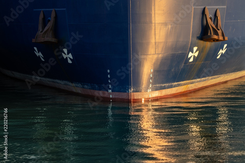 Big vessel in the port at sunset. Reflections of the ship in the water.