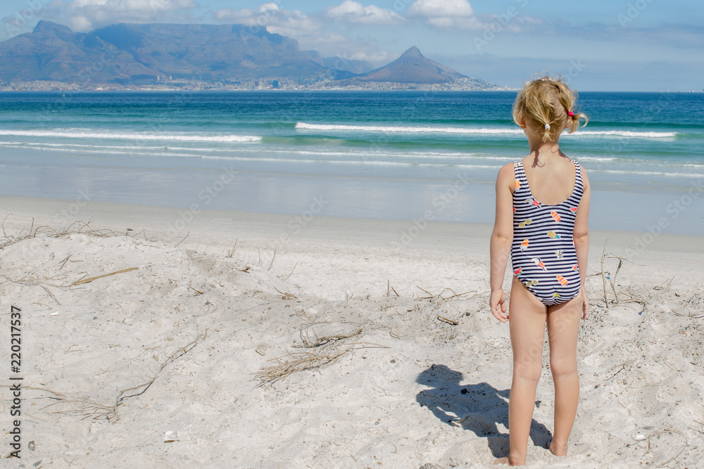 Little girl on the beach looking at Table Mountain