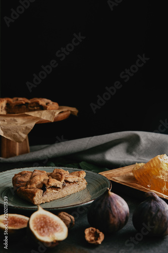 close up view of baked pie, beeswax and figs arranged on dark surface