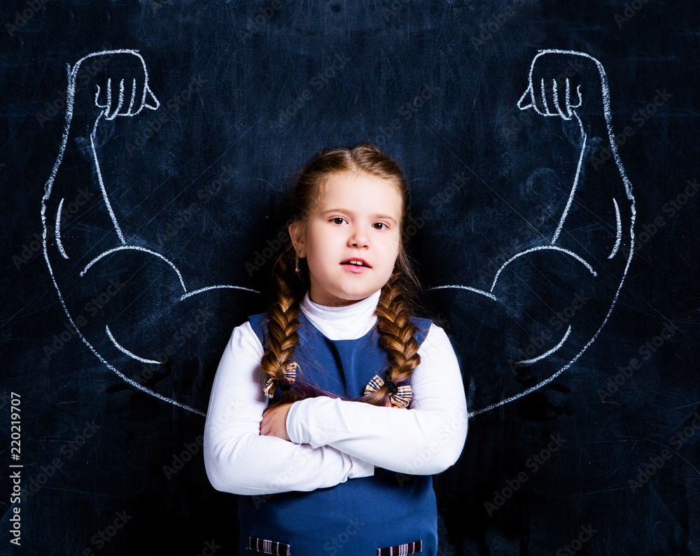 cute little schoolgirl against chalkboard with strong arms