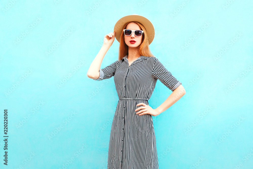 Fashion elegant young woman poses in a striped dress on a blue background Fashion elegant young woman poses in a striped dress on a blue background