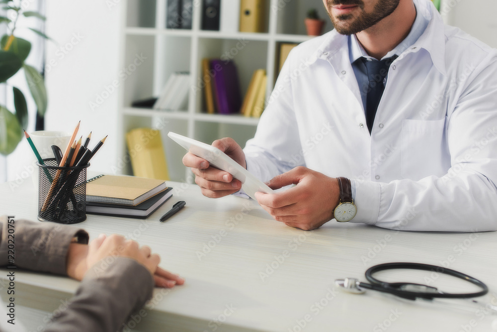 cropped image of doctor holding tablet in clinic cropped image of doctor holding tablet in clinic
