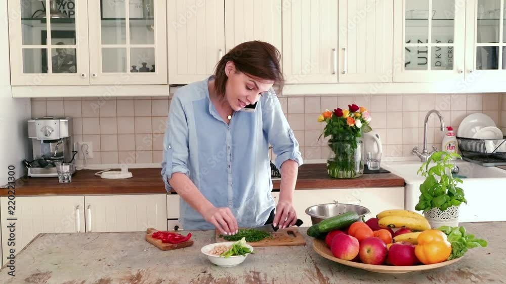 Pretty woman talking with someone by cellphone during preparing salad in the kitchen
Pretty woman talking with someone by cellphone during preparing salad in the kitchen
