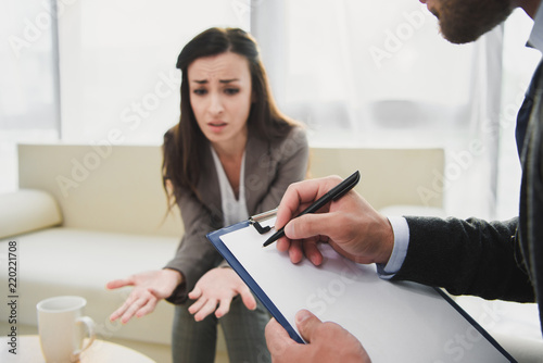 cropped image of crying patient talking and psychologist taking notes in doctors office