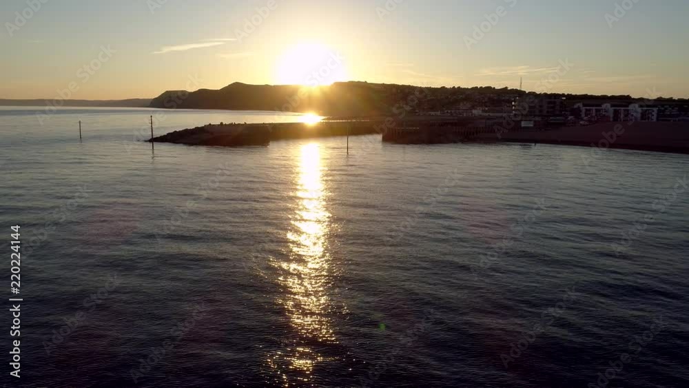 Drone flies low level towards harbor of West Bay Dorset during sunset. Drone flies low level towards harbor of West Bay Dorset during sunset.