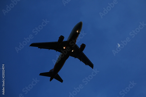 The airplane is flying against the blue sky in the sun