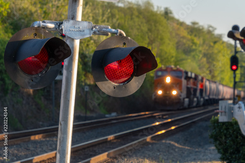 Close up of an active railroad crossing light with blurred on-coming train in background.