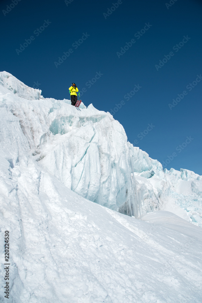 A freerider skier in complete outfit stands on a glacier in the North Caucasus. Skier preparing before jumping from the glacier