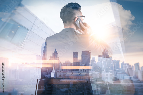 Photography The double exposure image of the businessman using a smartphone during sunrise overlay with cityscape image