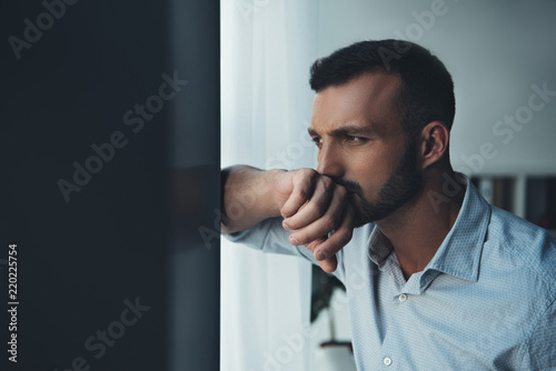 Fototapeta upset pensive man looking at window at home