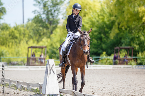 Teenage girl riding bay horse performing dressage test on equestrian competition © skumer
