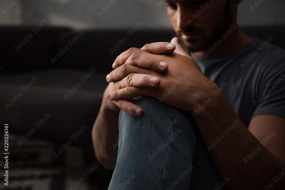sad man sitting on floor at home, selective focus