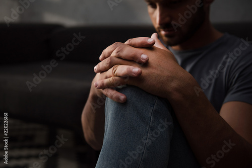 sad man sitting on floor at home, selective focus