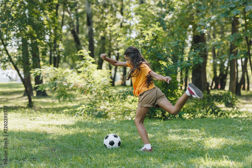side view of child kicking soccer ball in park side view of child kicking soccer ball in park