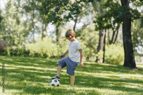 full length view of cute little boy playing with soccer ball in park