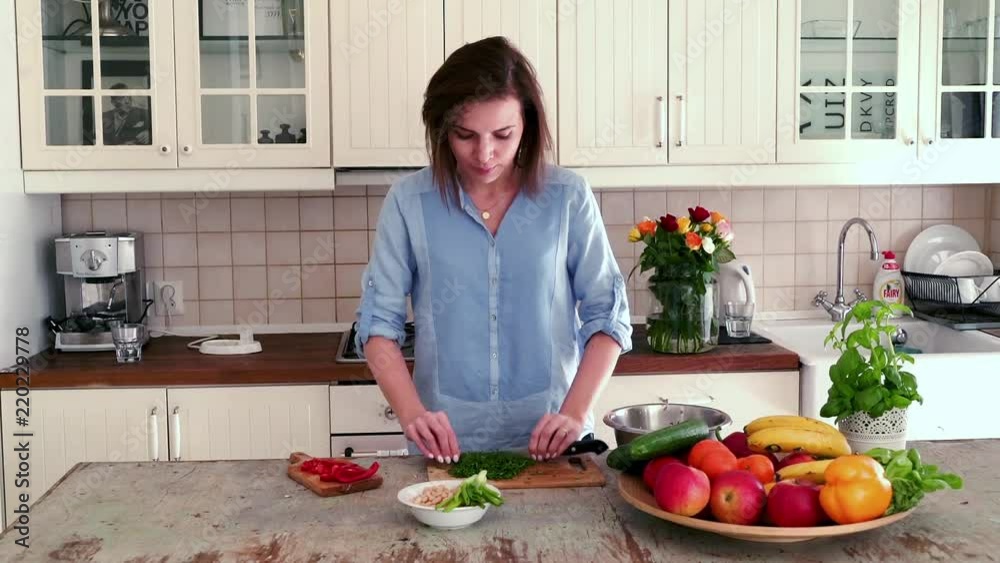 Pretty woman cutting parsley on the wooden board
Pretty woman cutting parsley on the wooden board