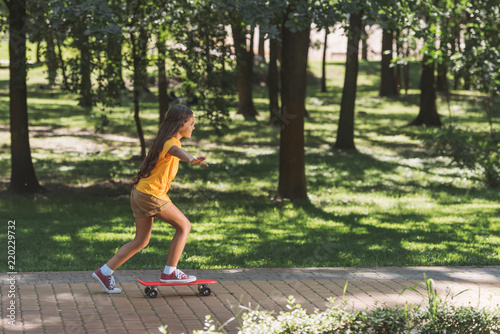 side view of cute little child riding skateboard in park photo