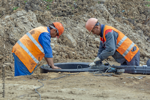 Quadro su tela Workers at the construction site welding stairs in the sewage well