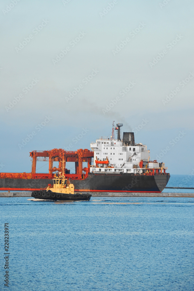 Tugboat assisting bulk cargo ship