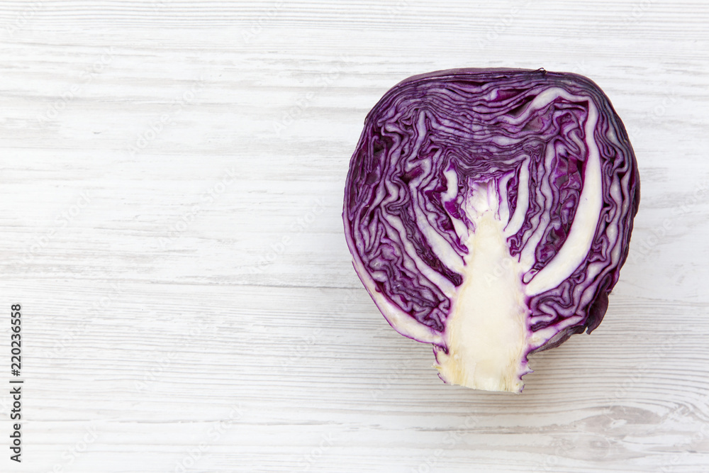 Fototapeta premium Half of red cabbage on white wooden background. From above, overhead, flat lay. Copy space and text area.